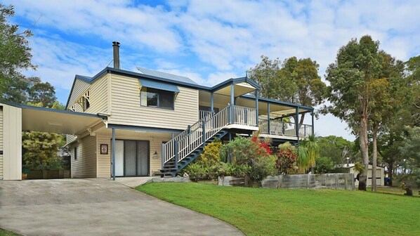 A two-story house with a covered front porch and a staircase leading to a balcony.