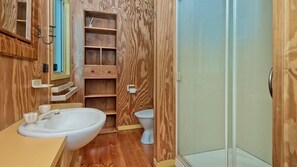 Une salle de bain avec des murs en bois, un lavabo, des toilettes et une douche.