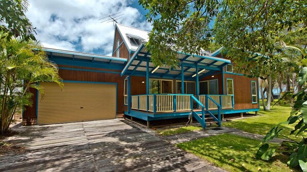 Une maison à deux étages avec un porche bleu, un garage et une pelouse bien entretenue.