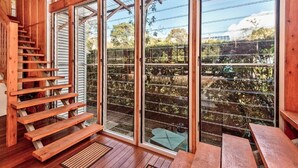 Una escalera de madera que lleva a una puerta de cristal con vistas a un jardín.
