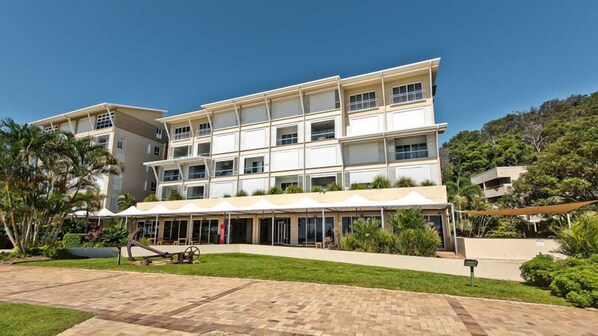 A multi-story hotel with a flat roof and a covered outdoor area with seating. - Deep Blue 8 (Moreton Island)