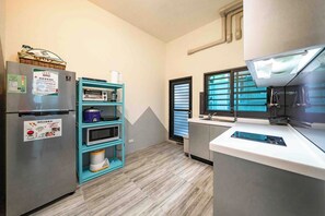 A compact kitchen with a refrigerator, microwave, and oven. - Chikan Fun Guesthouse (Tainan)