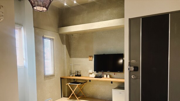 Ein Schlafzimmer mit Bett, Schreibtisch, Computer, Fernseher und Kleiderschrank.