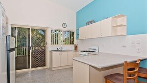 Eine Küche mit Gasherd, Kühlschrank, Spüle und einem Fenster mit Blick auf Grünflächen.