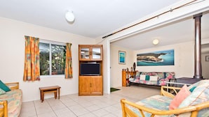 A spacious living room with a television, a sofa, and a fireplace. - Curlew Corner (Cowan Cowan)