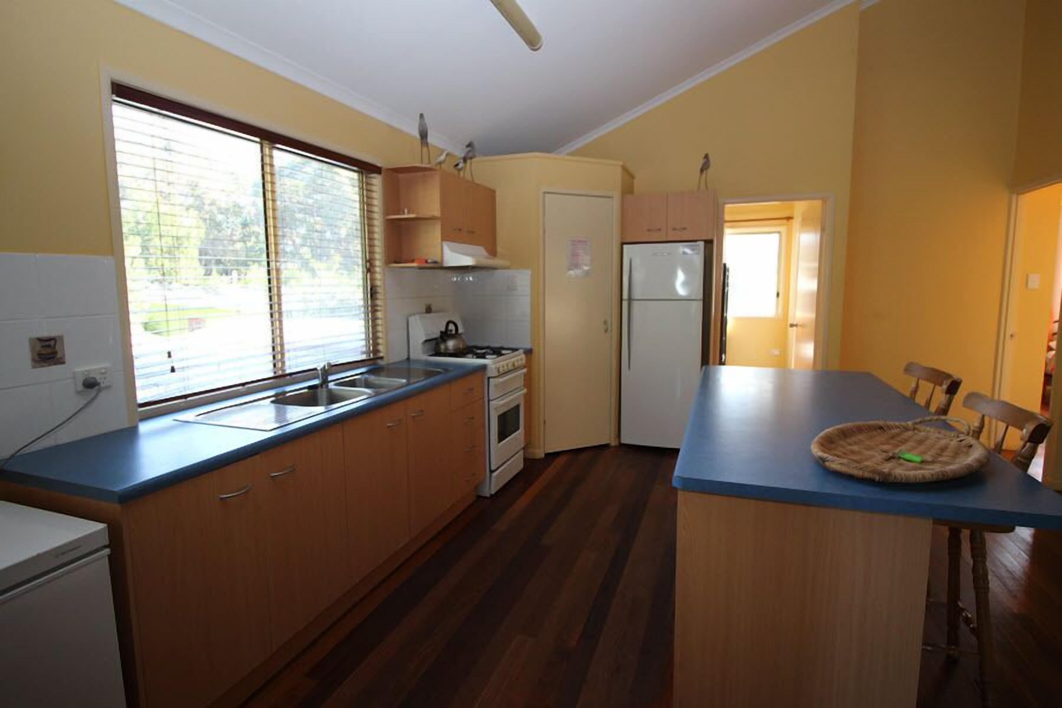 A compact kitchen with wooden cabinets, a built-in oven, and a refrigerator.