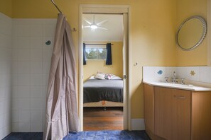 A bathroom with a shower curtain, a bed with a window, and a sink with a mirror.