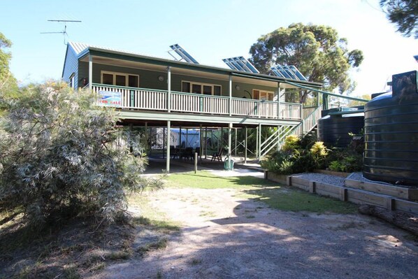 A two-story house with a balcony, solar panels, and a water tank.