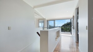 Ein modernes Interieur mit hohen Decken, einem Glastrennzaun mit Blick auf einen Balkon und einer Aussicht ins Freie.