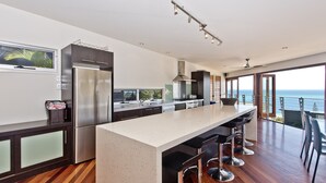 A modern kitchen with a large island, stainless steel appliances, and a view of the ocean.