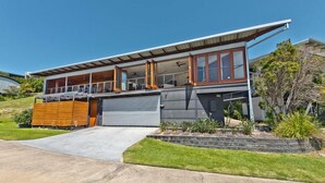 A modern two-story house with a large garage, a covered porch, and a well-maintained lawn.