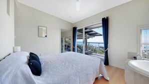 A bedroom with a large bed, a bathtub, and a balcony with a view. - Tangalooma Moreton Getaway (Moreton Island)