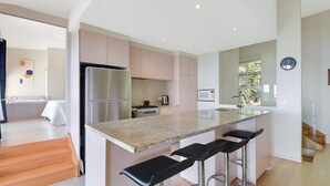 A modern kitchen with a large island, stainless steel appliances, and a minimalist design. - Tangalooma Moreton Getaway (Moreton Island)