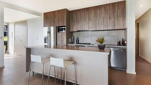 Una cocina moderna con una isla central, electrodomésticos de acero inoxidable y vistas al exterior.