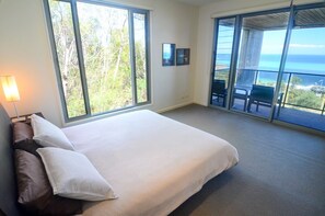 A bedroom with a large bed, a view of the ocean, and a balcony with outdoor seating. - Tangalooma Panoramic (Moreton Island)