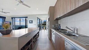Una cocina moderna con una isla central, electrodomésticos de acero inoxidable y vistas al exterior.