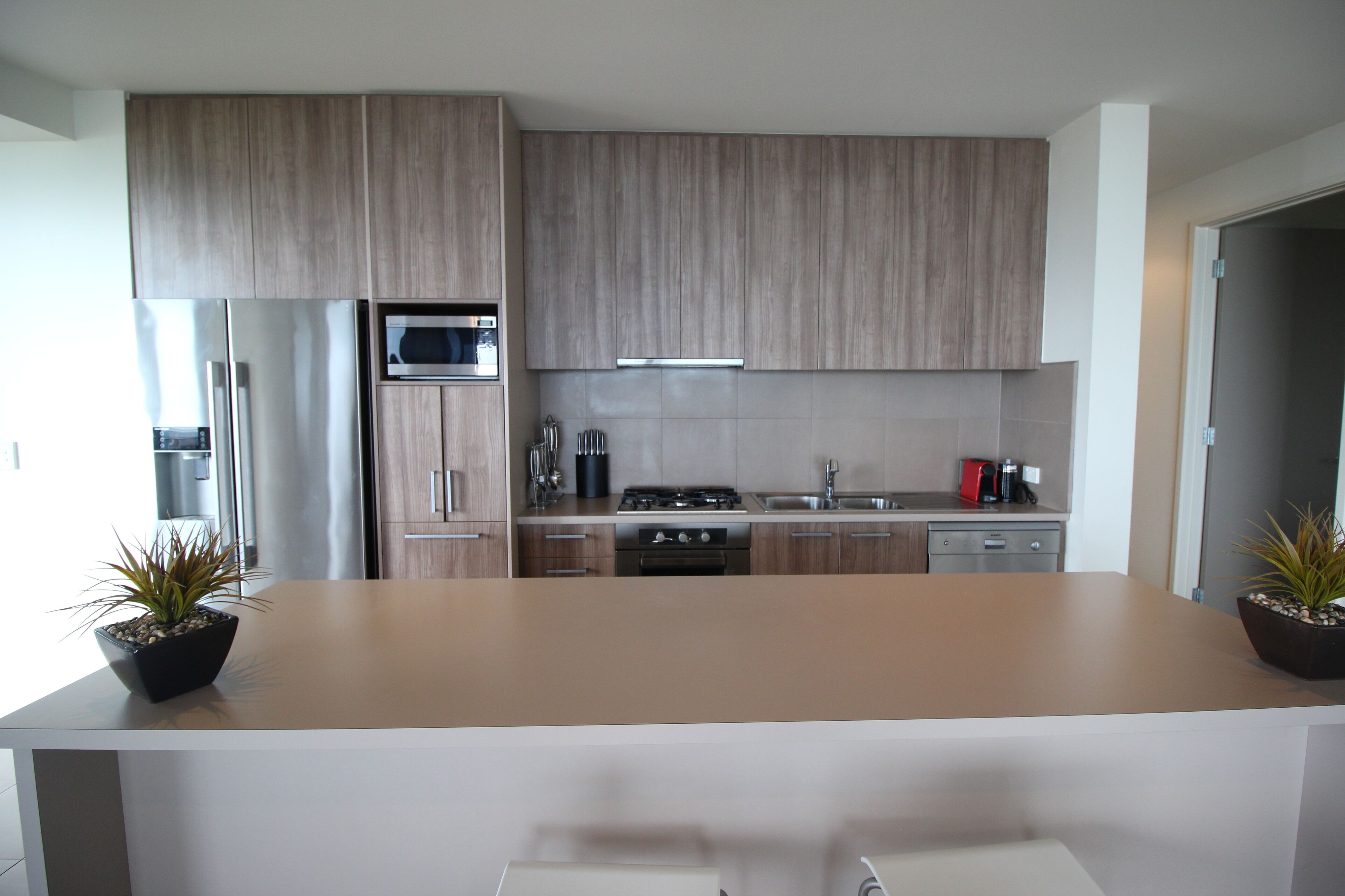 Une cuisine moderne avec des meubles en bois, des appareils électroménagers en acier inoxydable et un îlot central.