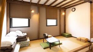 Una habitación japonesa tradicional con suelo de tatami, una mesa baja y camas futón.