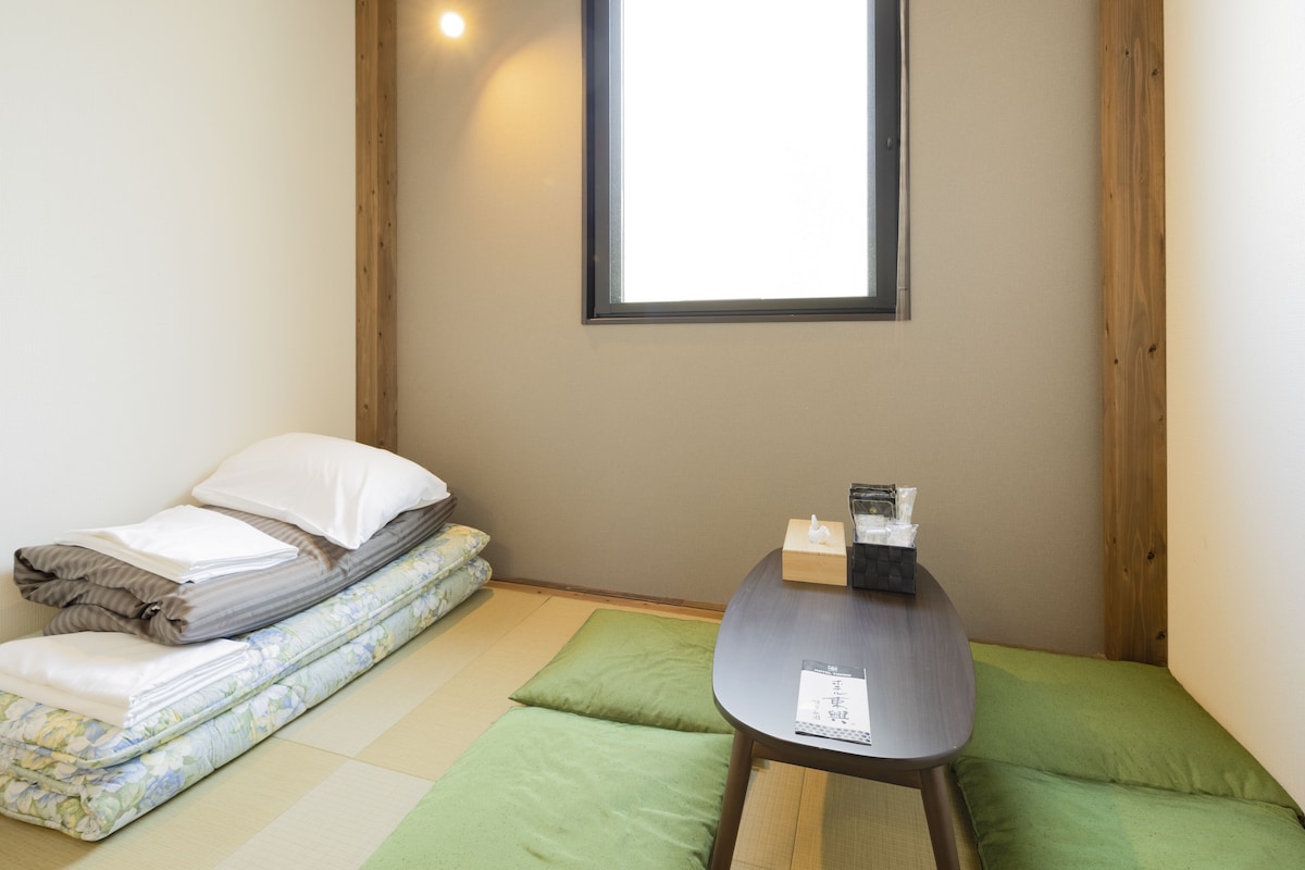 A small room with a bed, a table, and a window.