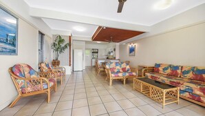 A spacious living area with wicker furniture, a tiled floor, and a view into the kitchen. - Villa at Tangalooma - Villa 14 (Moreton Island)