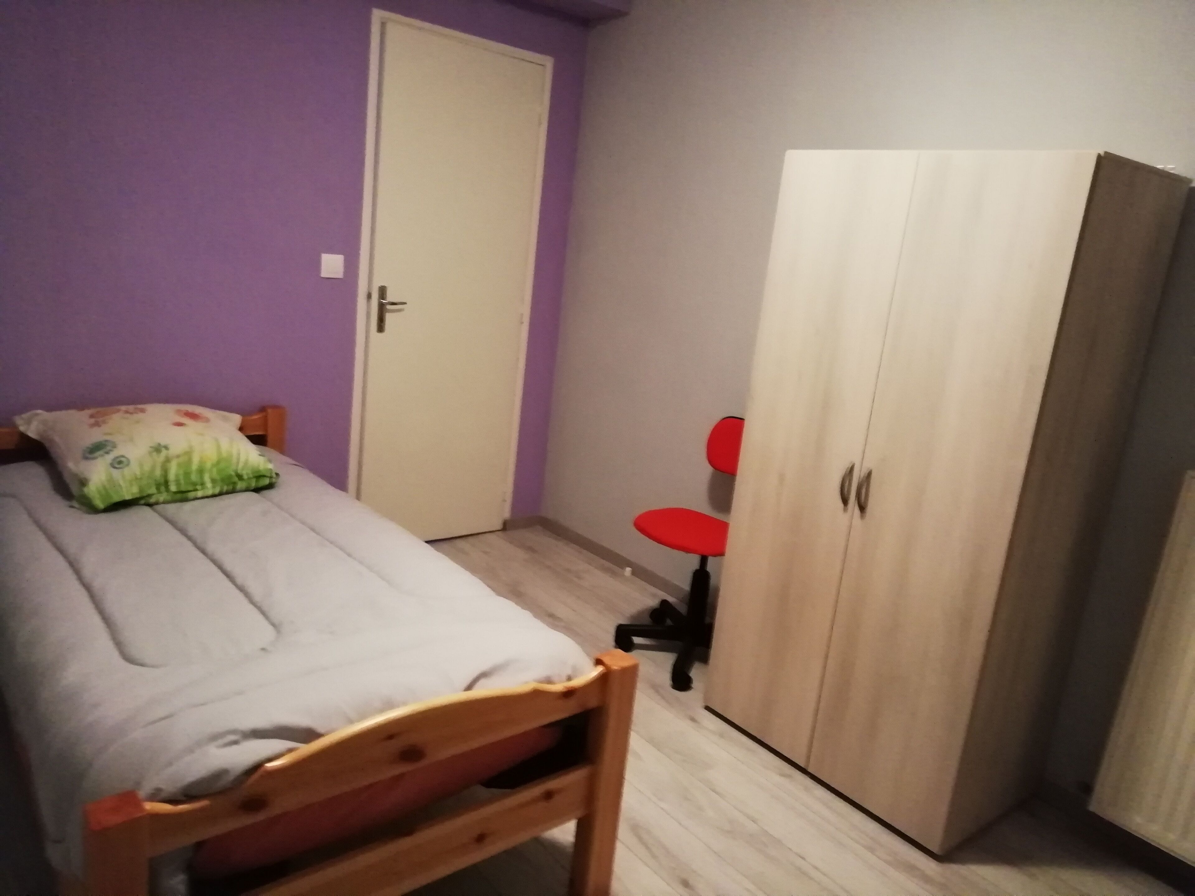 Una habitación pequeña con cama, armario y una silla.