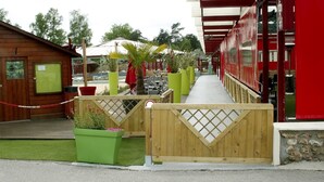 Een houten blokhut met een klein terras en een groene plantenbak.