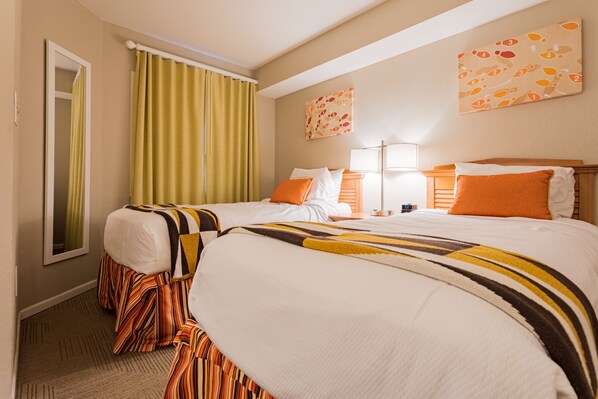 Two single beds with striped bed skirts, a bedside table, and a large window with a green curtain.