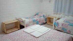 A small, clean room with two single beds, each with a wooden headboard and a floral-patterned bedspread. There are two bedside tables and a small wooden cabinet. - House - Mar Condominium Azul (Porto de Galinhas)