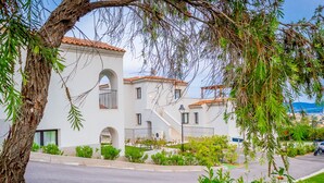 A row of white buildings with red-tiled roofs, a tree in the foreground, and a clear sky. -  Green Residence Olbia (Olbia)