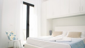 A modern bedroom with a large bed, white walls, and a view of the outdoors. -  Green Residence Olbia (Olbia)