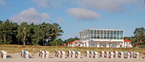 A beachside building with a modern design, surrounded by beach huts.