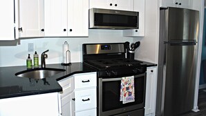 A modern kitchen with white cabinets, a stainless steel refrigerator, a microwave, and a stove. - Stylish Ocean Grove Apt - 4 Blocks from Beach & 2 Blocks from Downtown Asbury (Ocean Grove)
