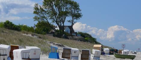 Une plage avec des chaises de plage, un bateau et une maison en arrière-plan.