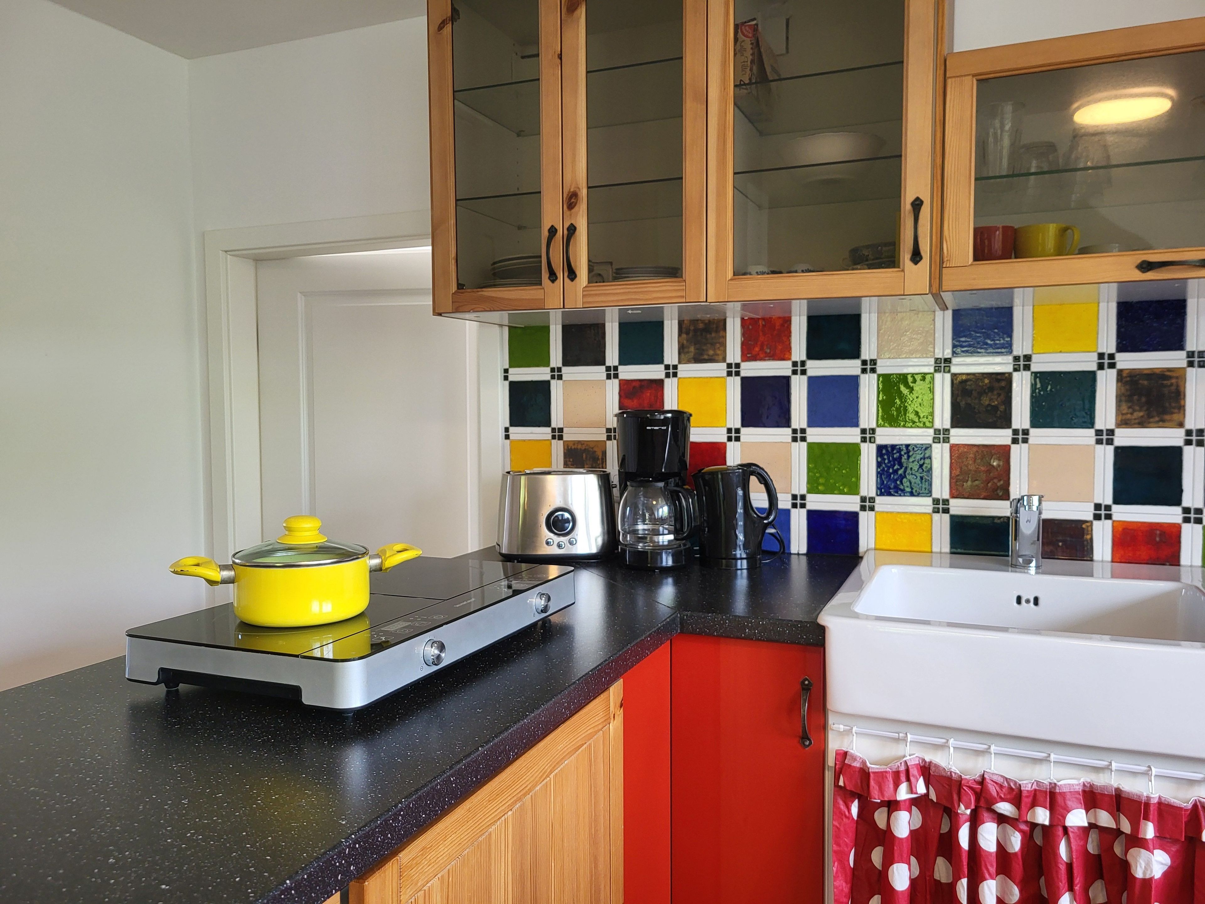 Een keuken met een fornuis, koffiezetapparaat en een vrolijke spatwand.