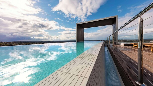 Une piscine à débordement située sur le toit, offrant une vue dégagée sur les gratte-ciel de la ville.