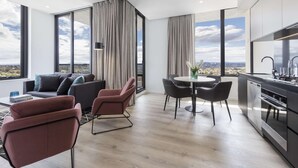 Un salon moderne comprenant un canapé, des fauteuils, une table à manger et un coin cuisine avec vue sur la ville.