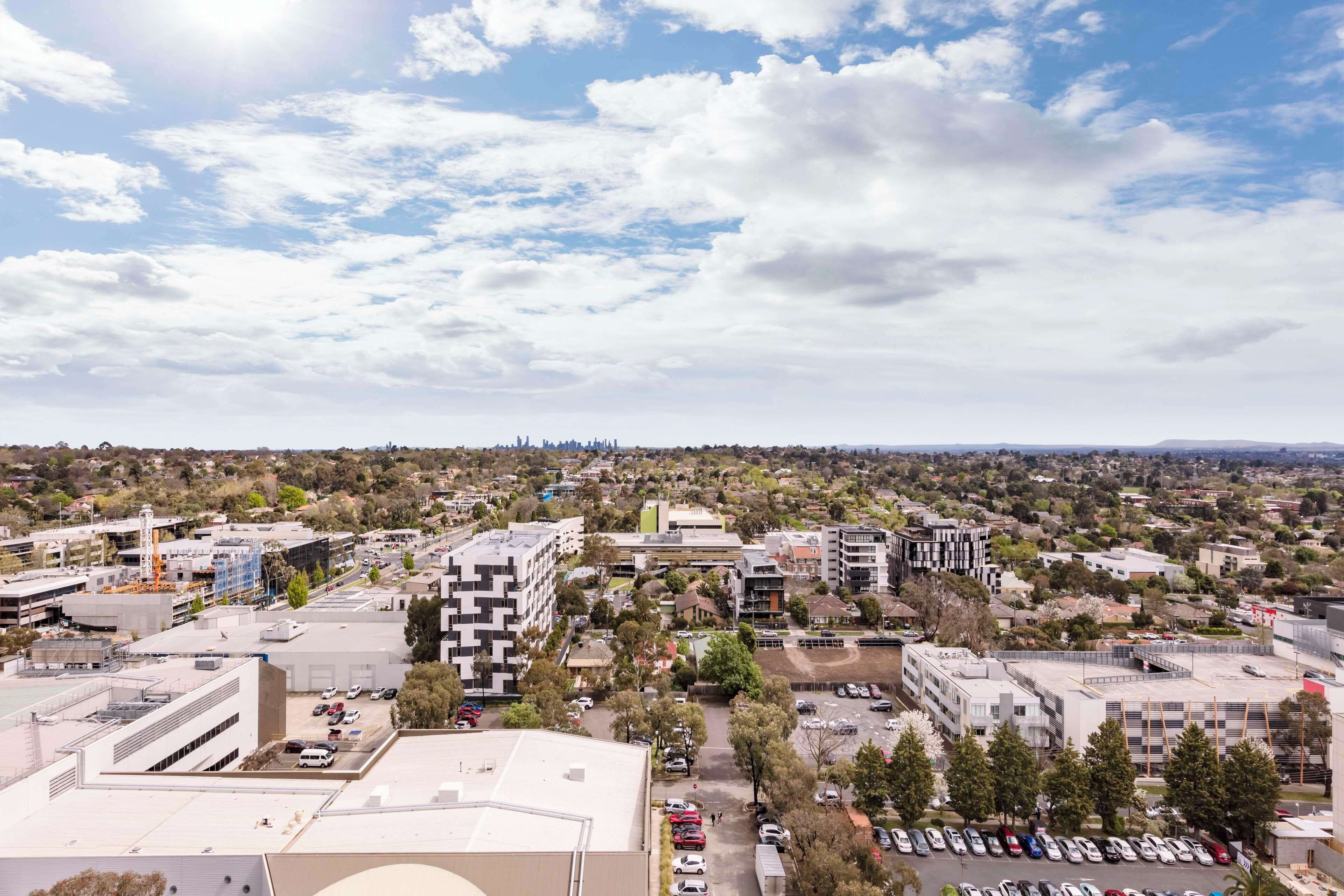 A cityscape with modern buildings, a parking lot, and a distant skyline.