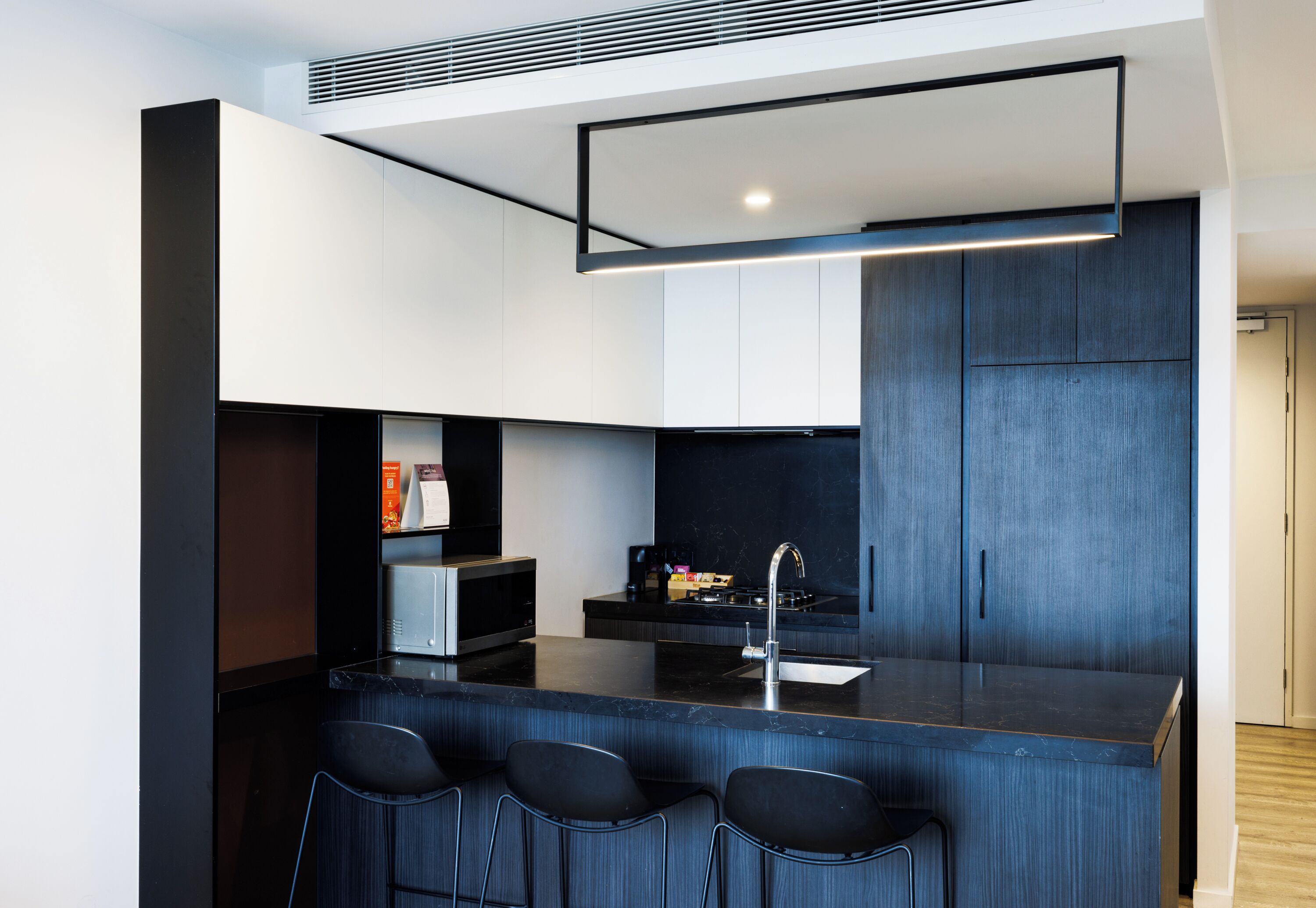 A modern kitchen with a central island, bar stools, and built-in appliances.