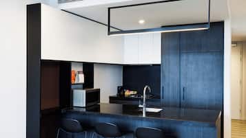 A modern kitchen with a central island, bar stools, and built-in appliances.