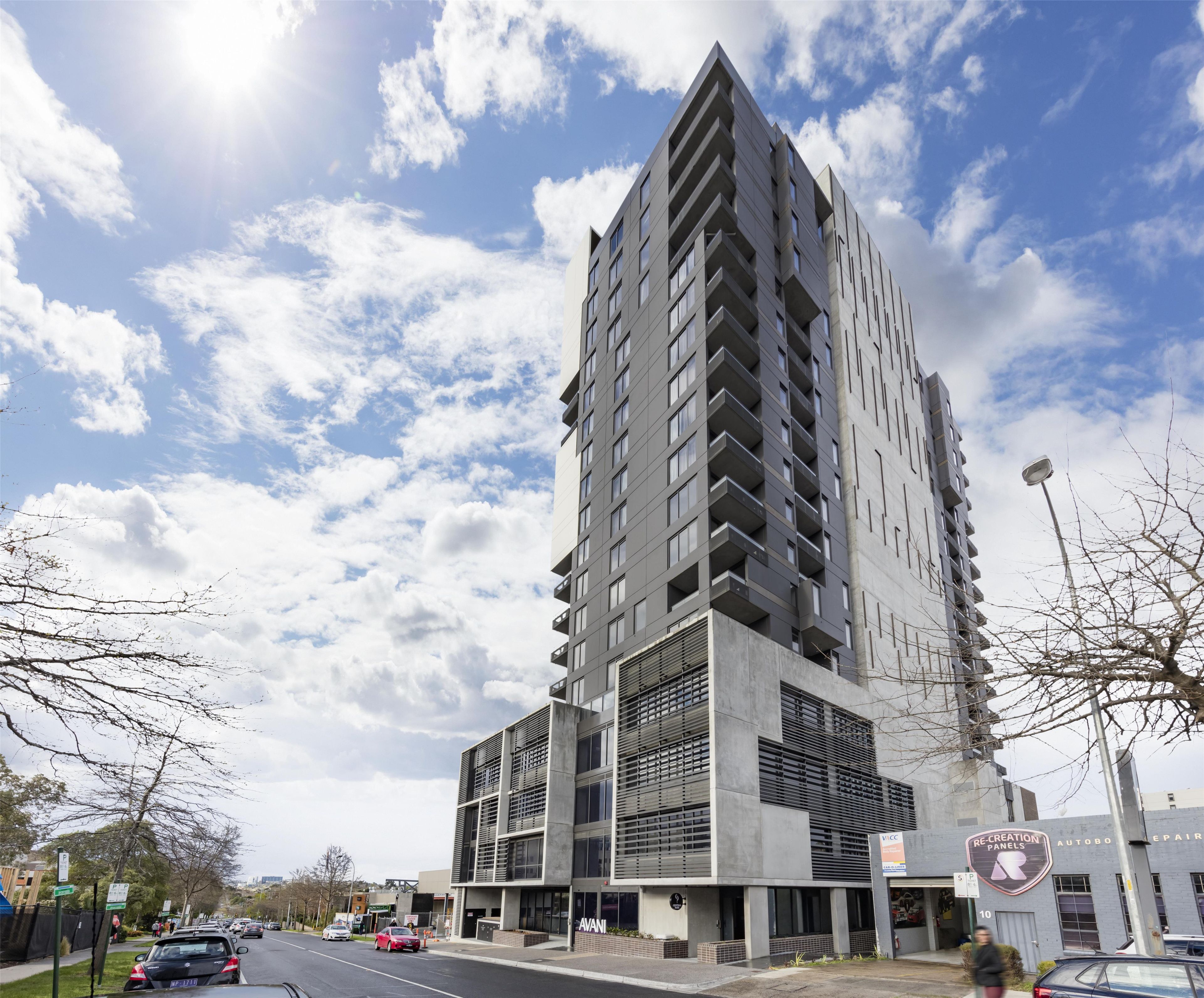 A modern multi-story building with a prominent corner design, large windows, and a visible storefront with signage.