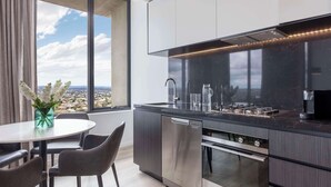 Une cuisine moderne dotée d’un four encastré, d’un lave-vaisselle et d’une grande fenêtre offrant une vue sur la ville.