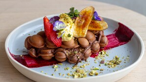 A plate of chocolate profiteroles with strawberries, pistachios, and a decorative beetroot puree. - Avani Melbourne Box Hill Residences (Box Hill)