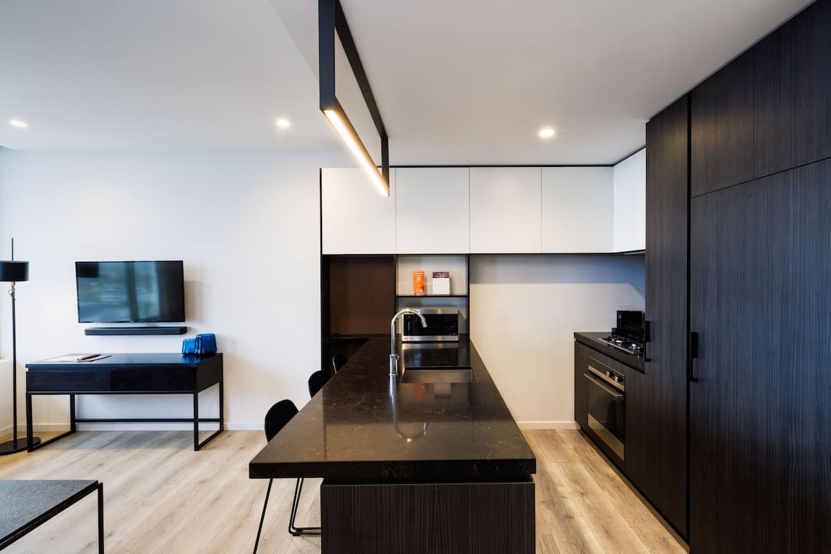 A modern kitchen with a central island, built-in appliances, and a flat-screen TV mounted on the wall.