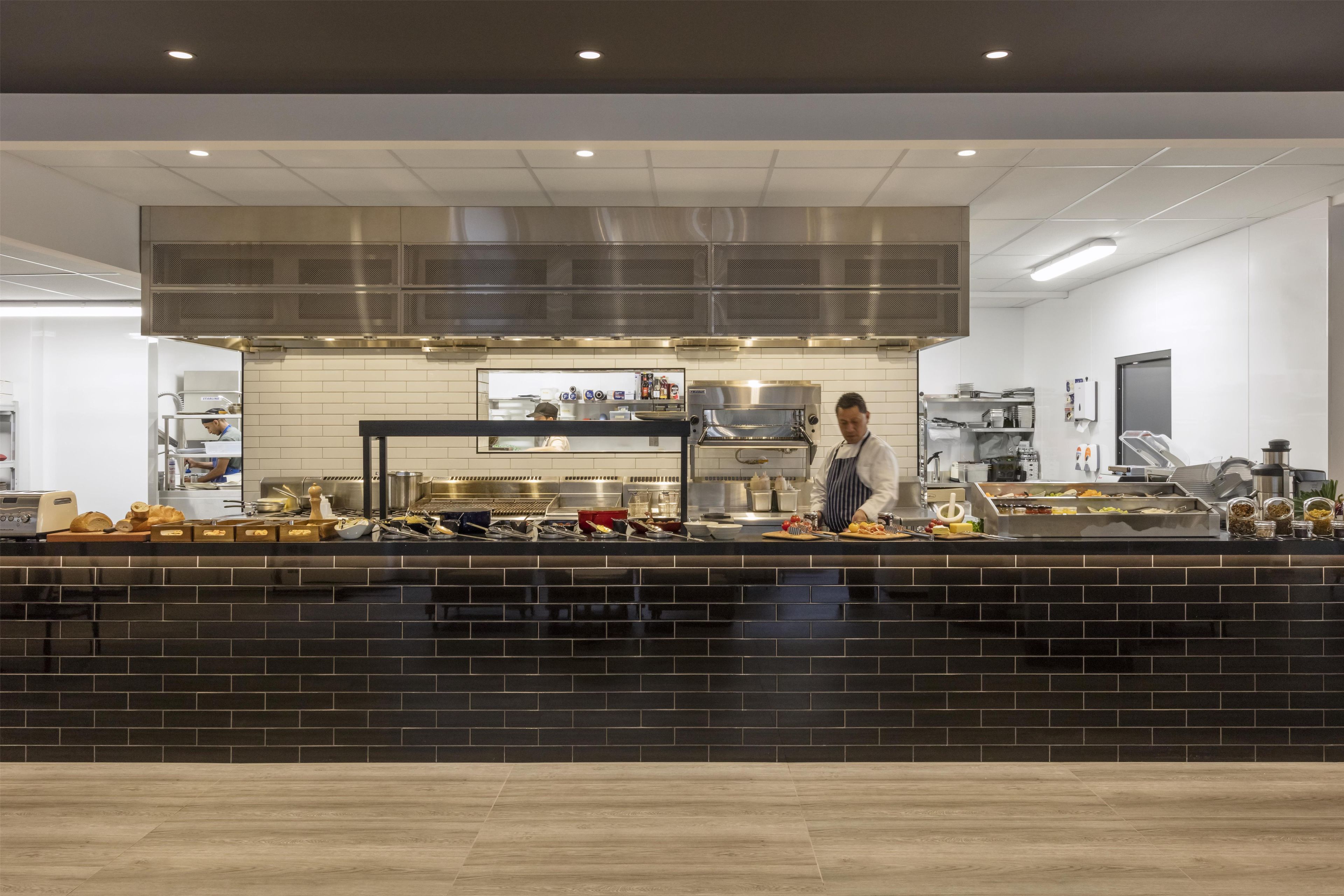 A modern kitchen with a black countertop, stainless steel appliances, and a large ventilation hood.