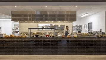 A modern kitchen with a black countertop, stainless steel appliances, and a large ventilation hood.