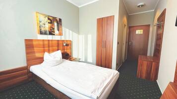 Une chambre d’hôtel avec un lit, une armoire en bois et un tableau au mur.
