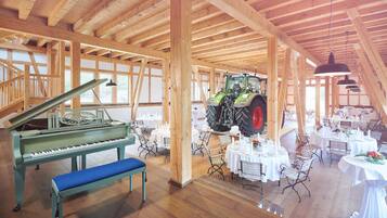 Een ruime hal met een vleugel, een tractor en tafels gedekt voor een evenement.