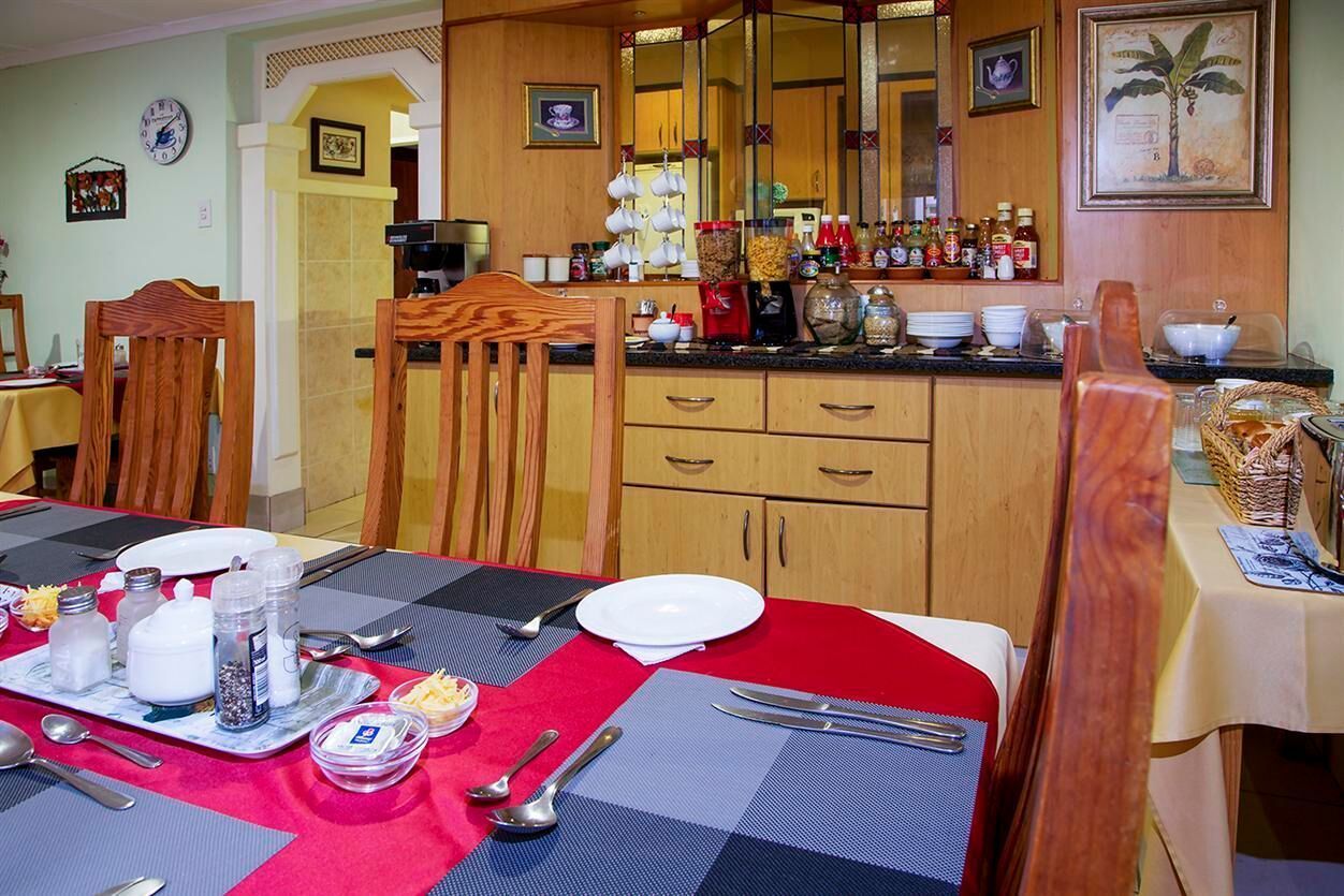 Un comedor con mantel rojo, sillas de madera y una mesa de buffet.