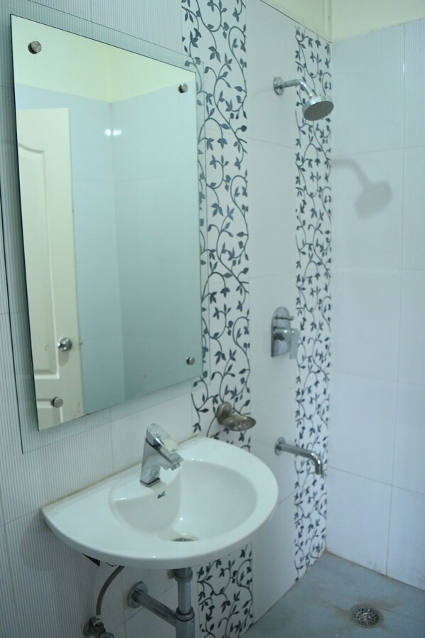 A bathroom with a white sink, a mirror, and a shower.