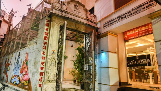 A building with a mural depicting deities, a restaurant named Ganga Darshan, and a signboard with a date. - Ganga Darshanam Guest House (Varanasi)